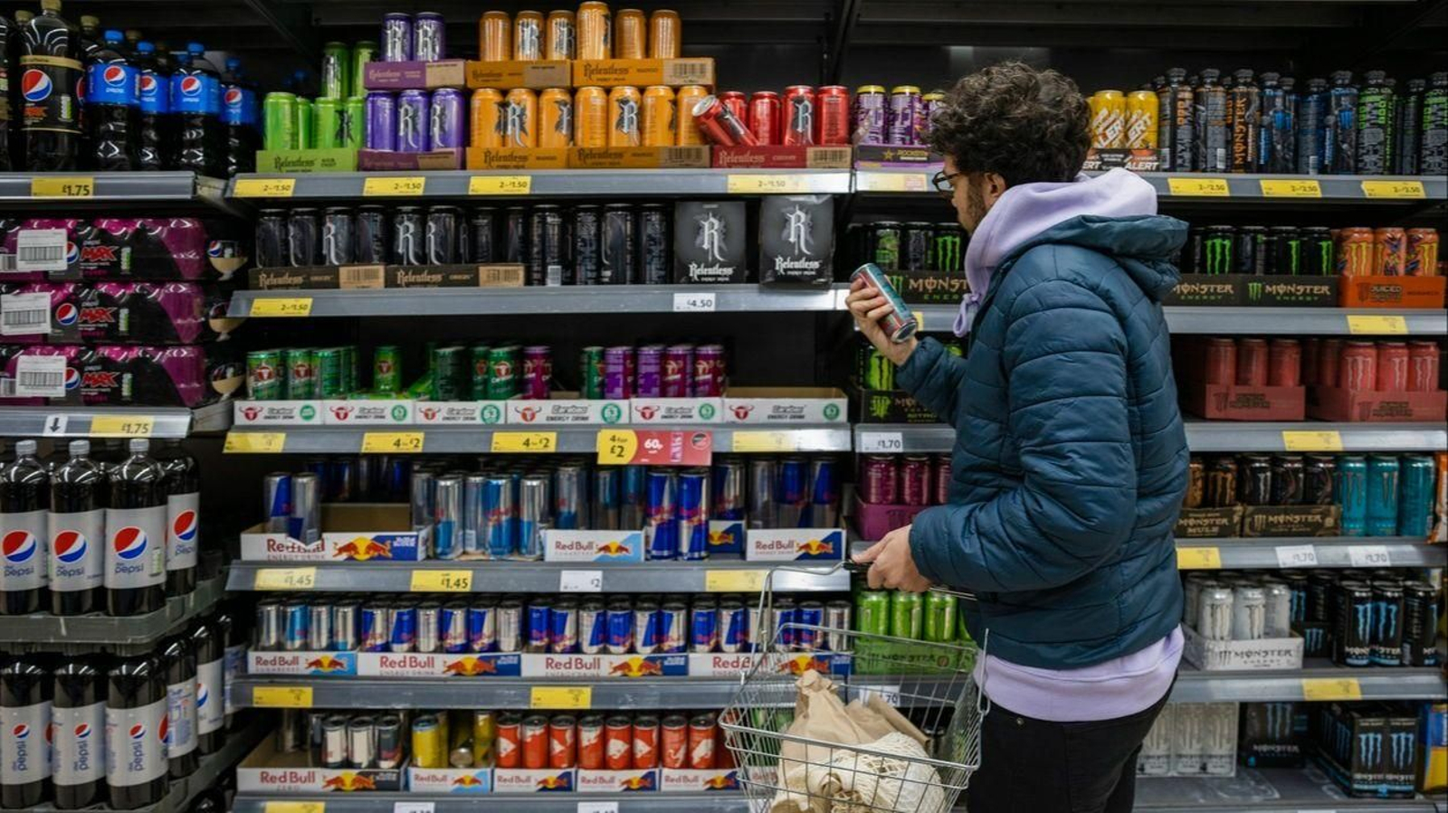 Un joven mira la sección de bebidas energéticas en el supermercado.