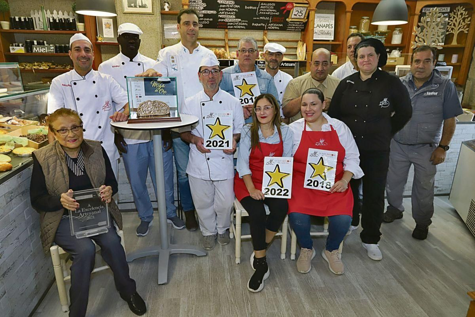 Adolfo Villafines posa su mano sobre la “Miga de oro” rodeado de sus compañeros y su madre en el despacho del alto de Mallón en Nigrán