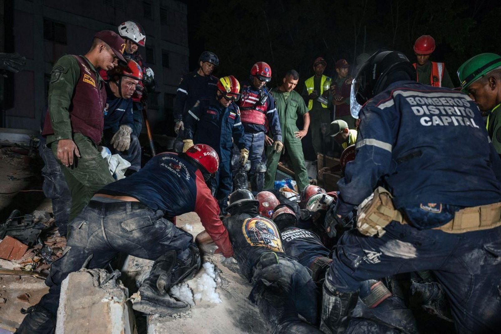 Equipos de rescate se afanan en un edificio colapsado de Caracas en busca de posibles supervivientes.