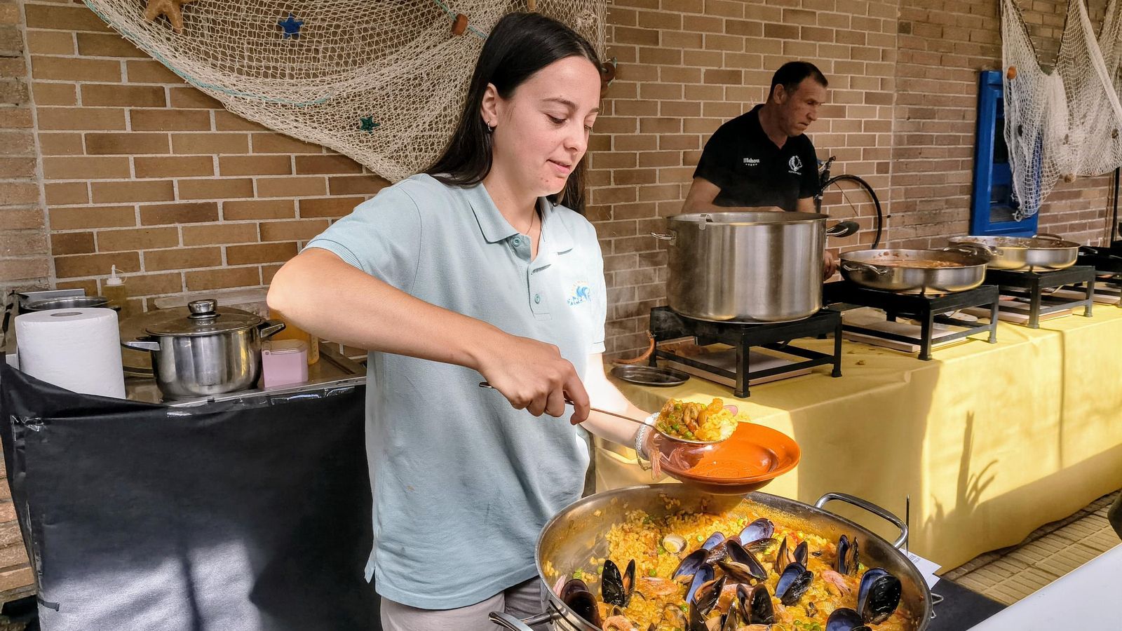 Una de las cocineras sirve una ración de arroz de marisco.