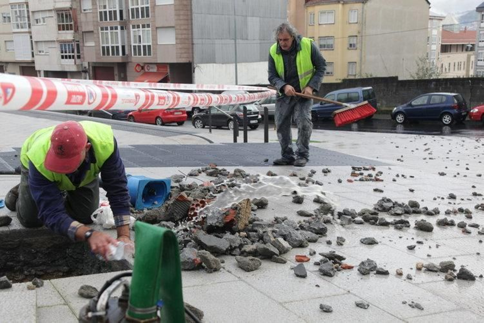 Dos operarios se afanan por reparar la avería, tras levantar parte de la acera, de reciente construcción (JOSÉ PAZ)