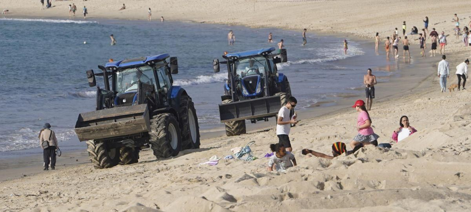 La maquinaria del Concello en la playa de Samil realizando trabajos de limpieza y explanación coincidió con los primeros bañistas.