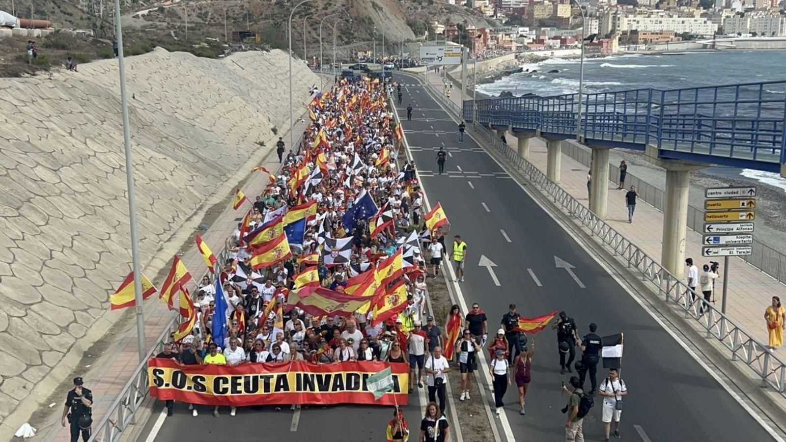 Cientos de ceutíes portan una pancarta con el lema “SOS Ceuta invadida”.