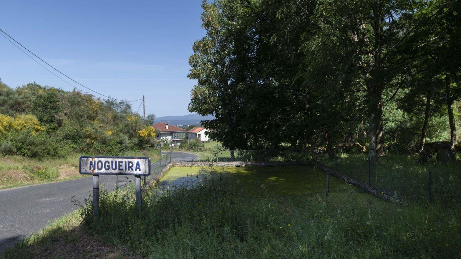 La entrada de la aldea de Nogueira y su tanque de agua para emergencia de incendios, en estado de abandono