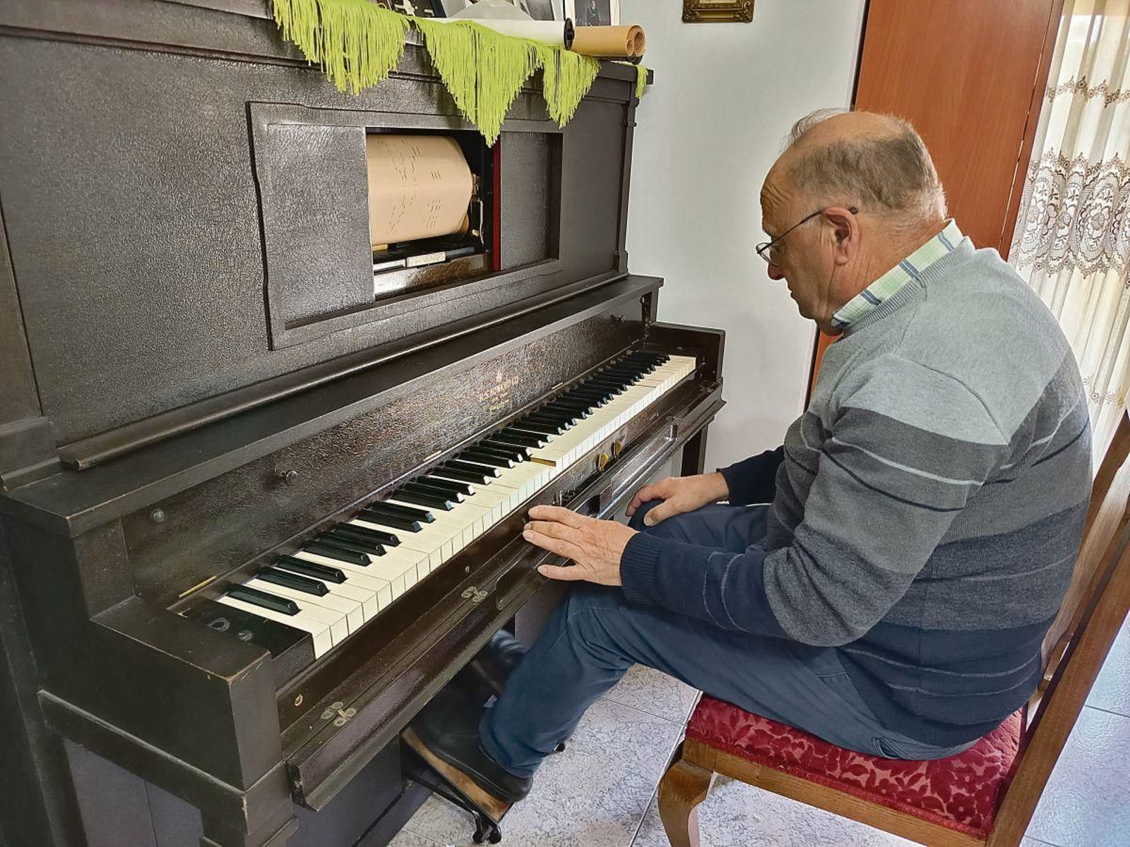El coleccionista tocando su pianola de rollo de más de cien años comprado en el Rastro de Madrid.