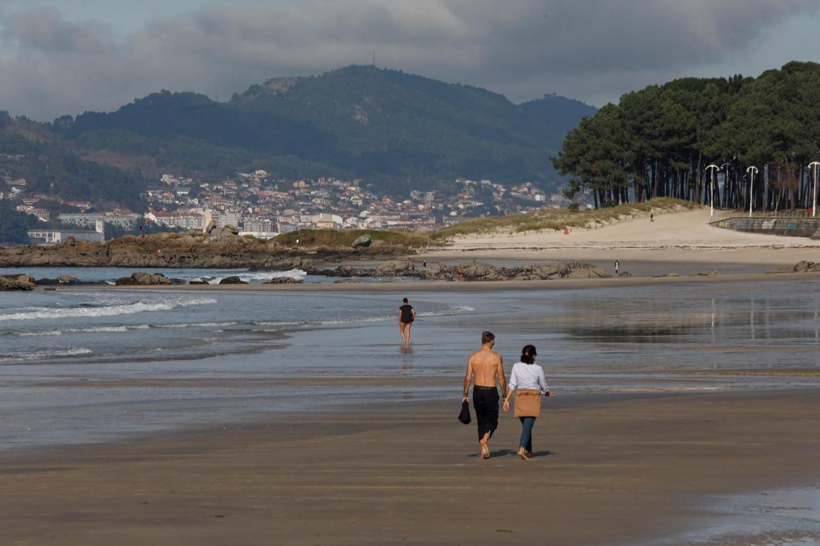 Paseantes sobre la arena de Samil.