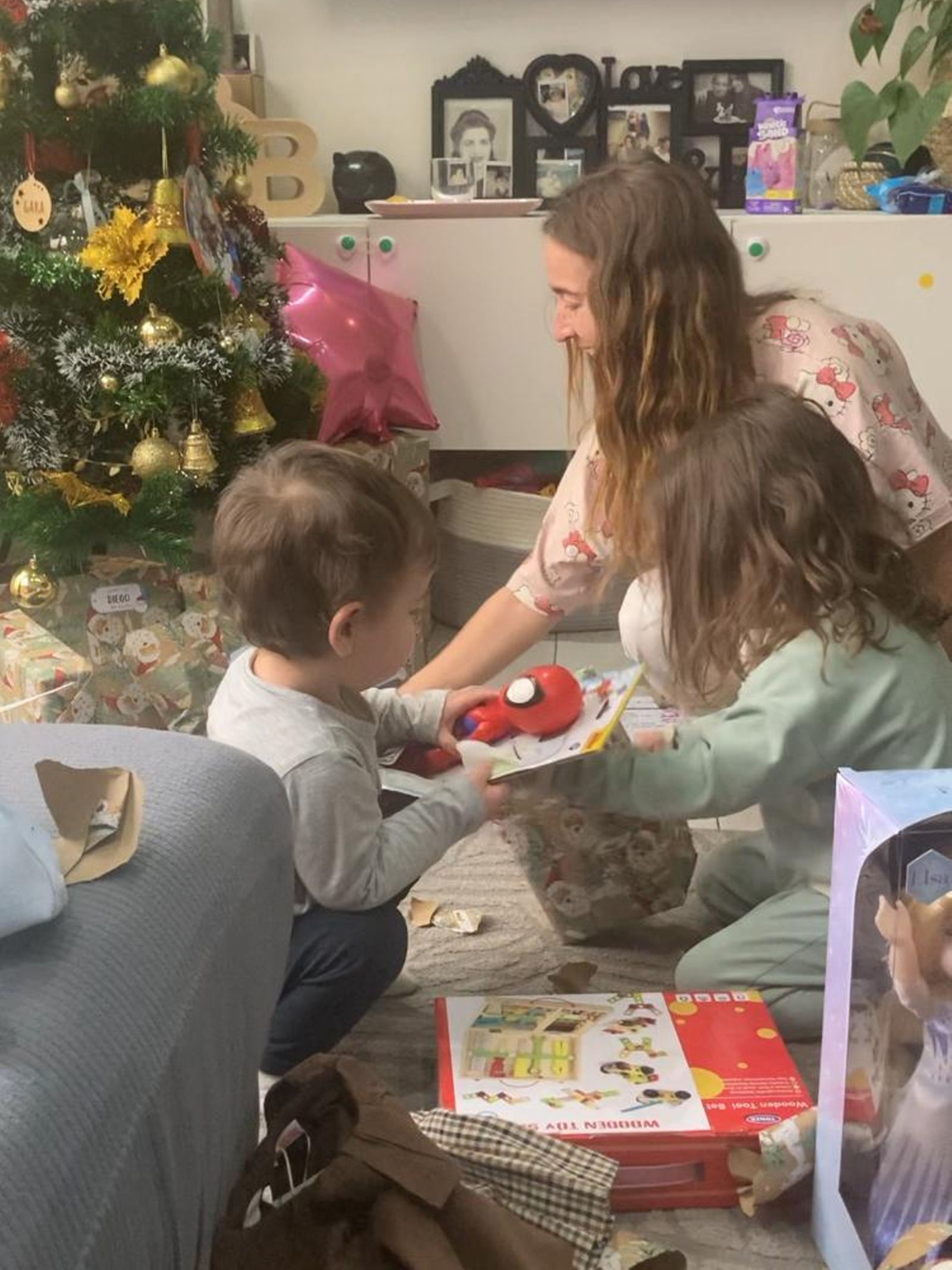 Los niños abren sus regalos al lado del árbol de Navidad