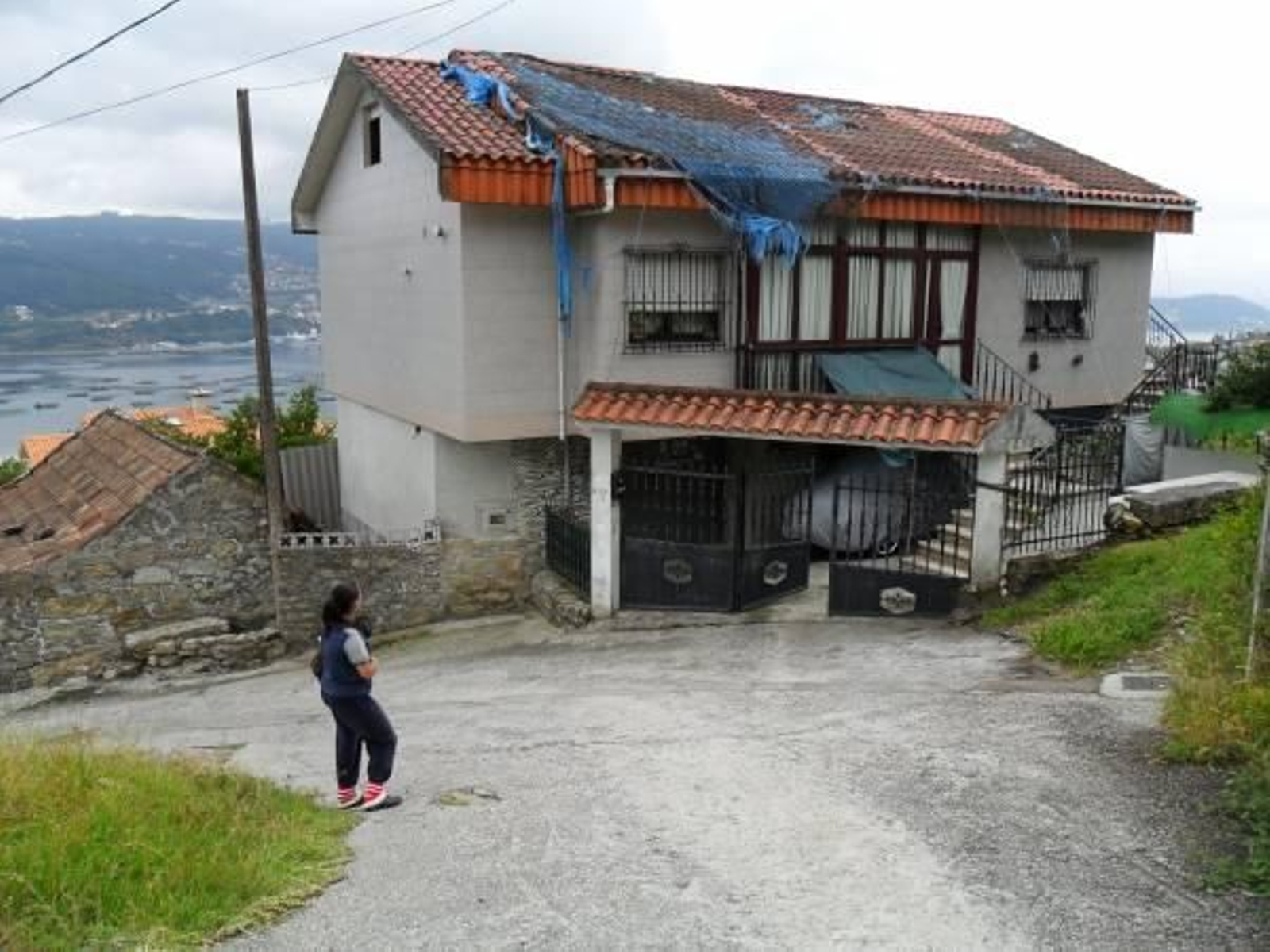 La casa, situada en la parte alta de la parroquia de Domaio, lleva varios años con la lona y red.