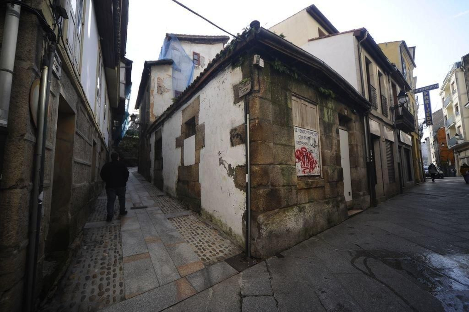 Un vecino pasea por la Canella Cega, tras dejar edificios abandonados de la rúa do Vilar.