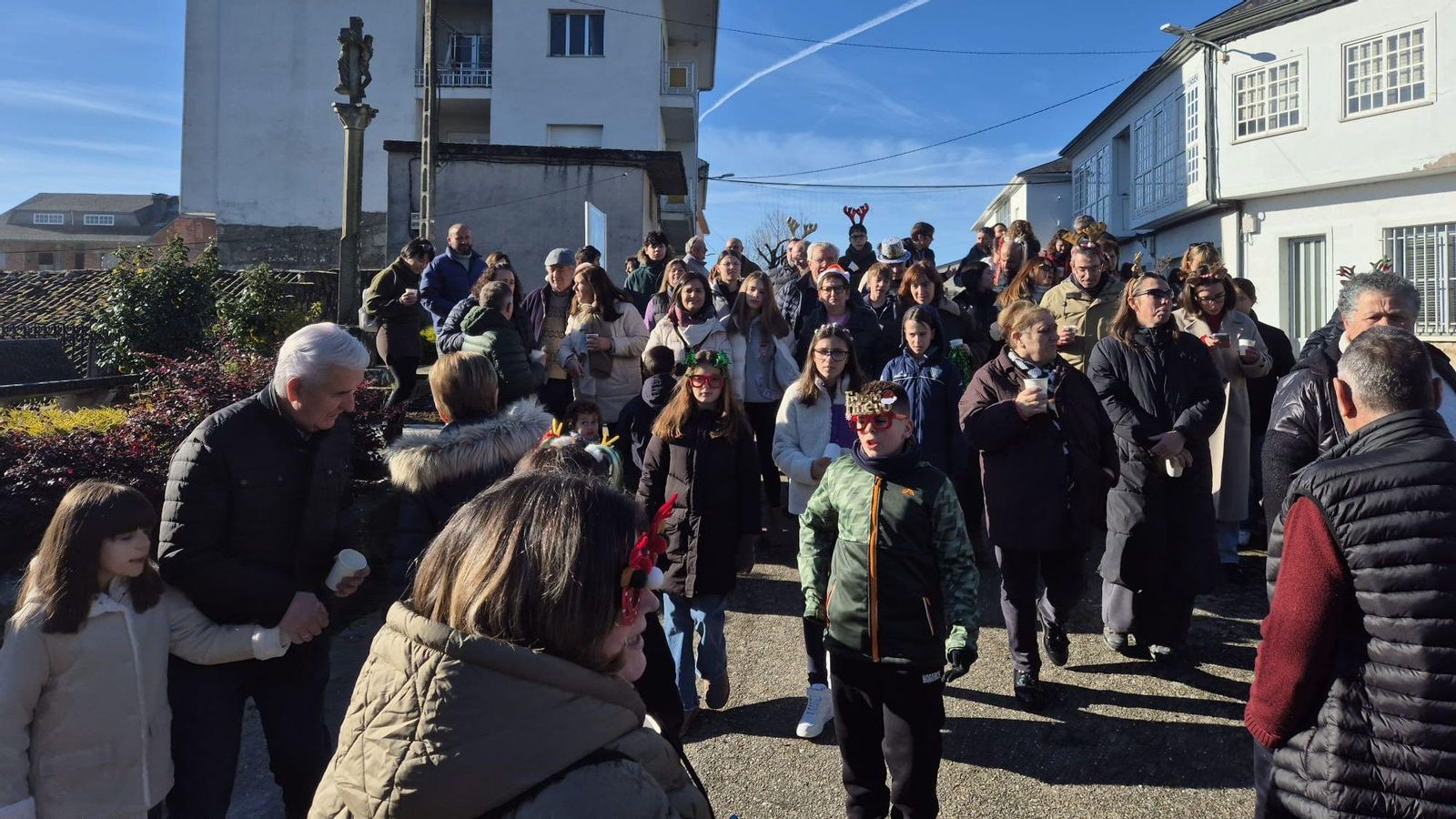 Veciños e veciñas celebran as Prebadaladas comendo as uvas, con gorros e atavíos festivos, no centro de San Xoán de Río.