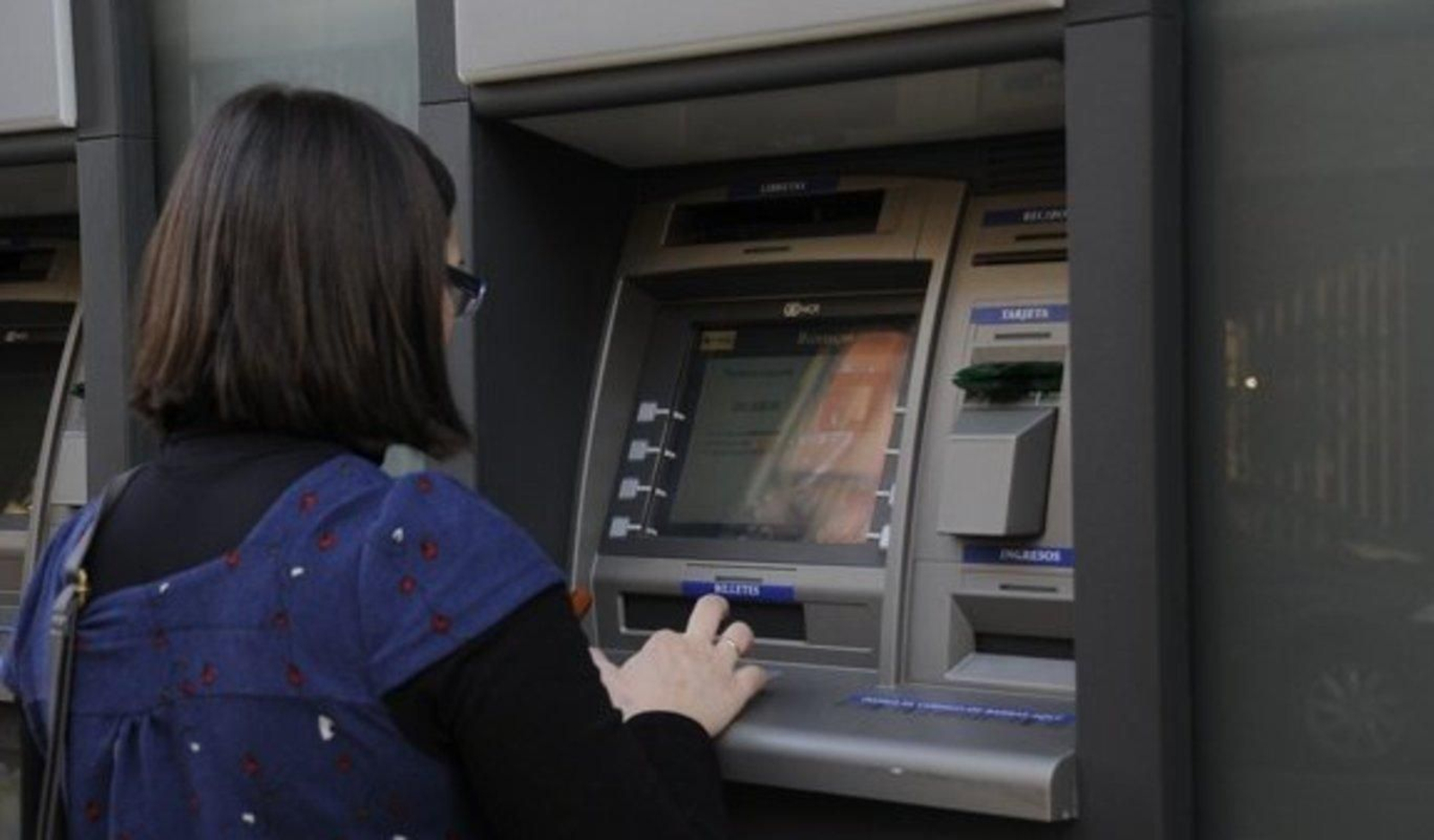 Una mujer trata de sacar dinero en el cajero automático de una sucursal bancaria.