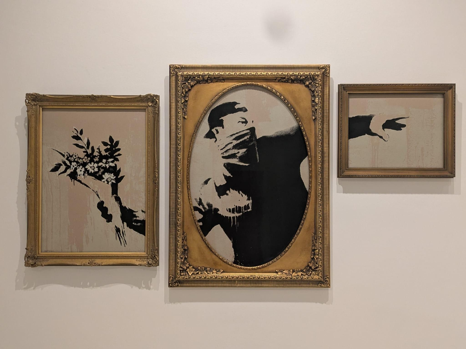 Esta imagen muestra el "Flower Thrower Triptych" (Tríptico del Lanzador de Flores) del artista urbano Banksy.