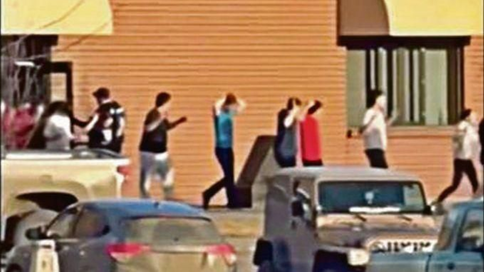 Los alumnos menores salen de la escuela secundaria de Tumbler Ridge con las manos en alto tras el tiroteo.