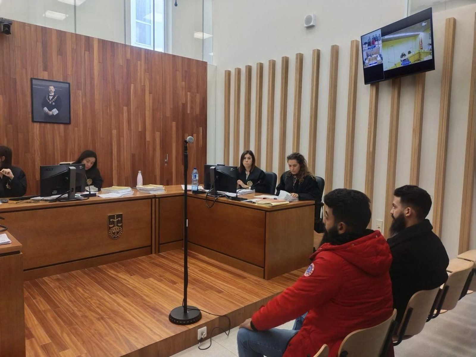 Tres de los acusados (uno por videoconferencia) en el juicio.