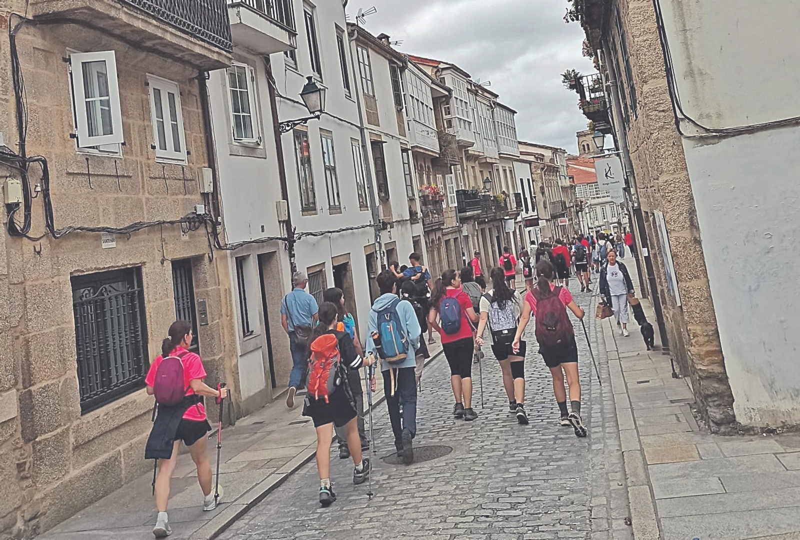 Peregrinos bajan por el medio de la Rúa de San Pedro, en Santiago de Compostela.
