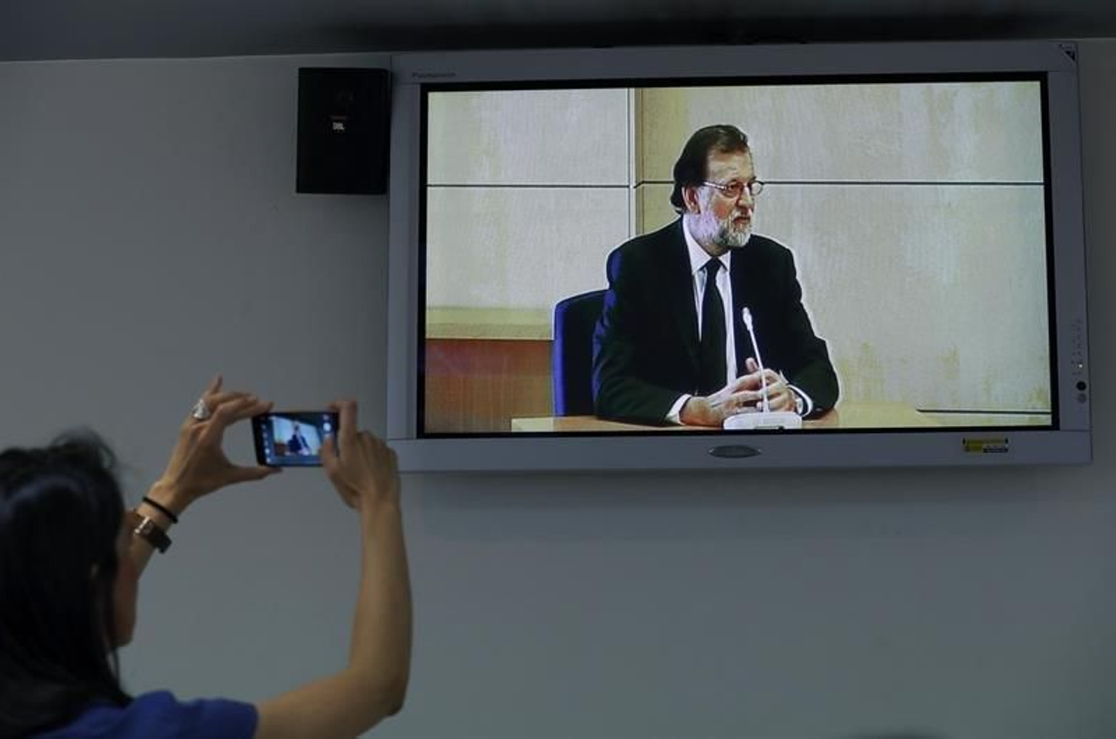 Una periodista toma una foto de Rajoy declarando.