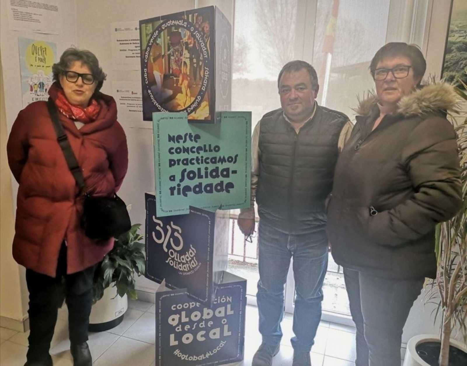 El alcalde y dos ediles ante el tótem instalado en el Concello.