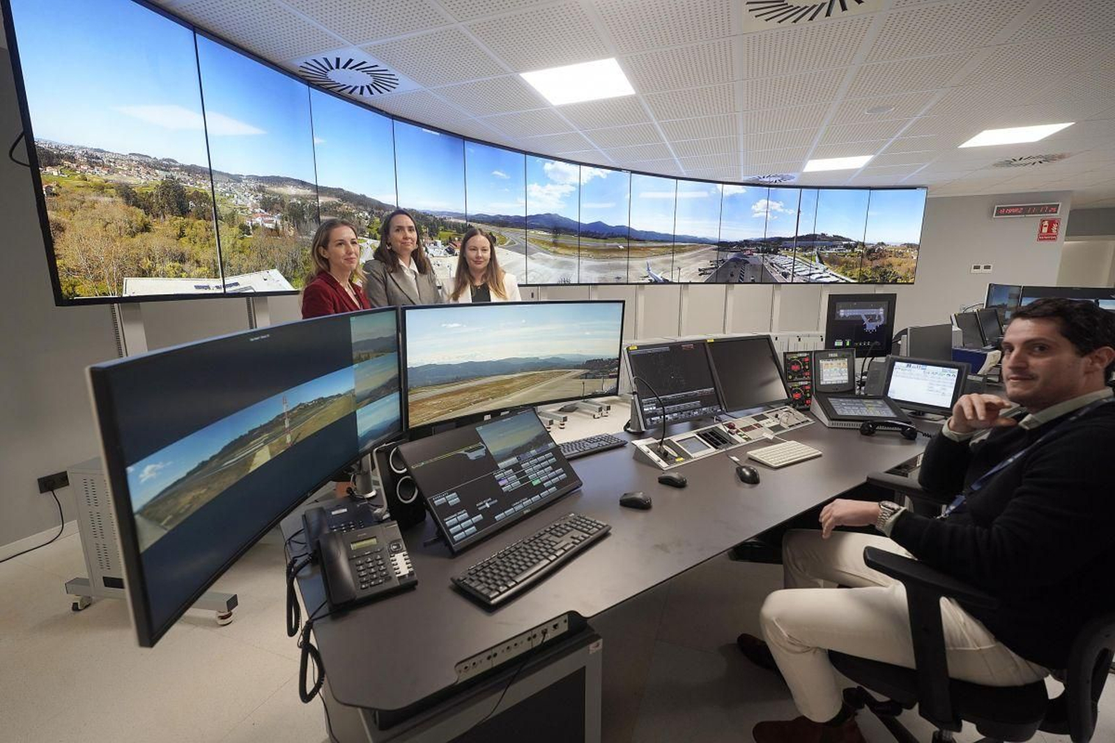 Ana Molés, Gema Martín y Lesly Iglesias posan frente a las 13 pantallas de 55 pulgadas dispuestas en el edificio anexo al aeropuerto.