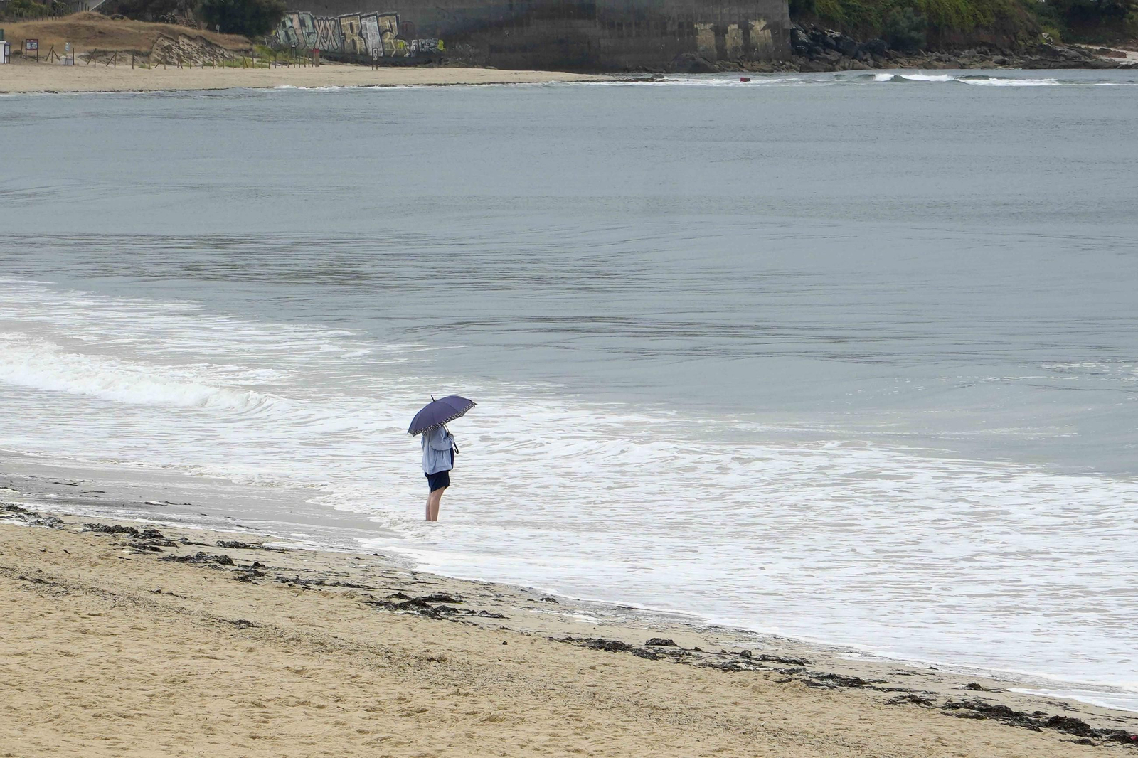 La lluvia vació ayer las playas aunque algunos decidieron meterse en el mar incluso con paraguas en mano.