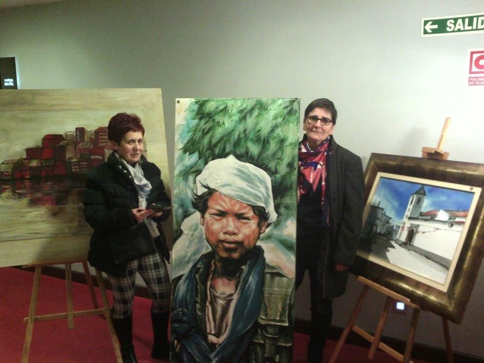 Pilar López y Pilar Muñoz, con tres de los cuadros que están a la venta para recaudar fondos.