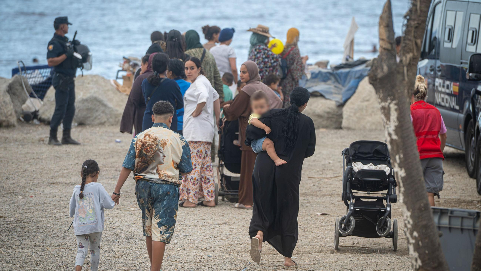 Varios migrantes recogen comida y bebida de Cruz Roja en la playa del Trampolín, a 23 de septiembre de 2026, en Ceuta (España)
