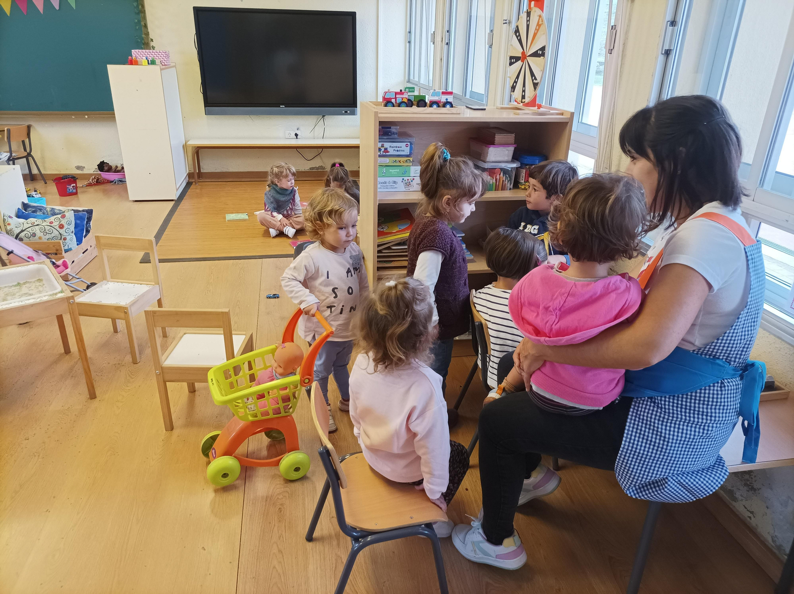 Un grupo de niñas y un niño hacen piña con la profesora de Infantil. (P.P.)