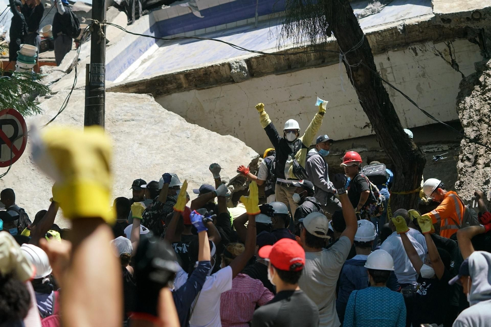 Rescatistas levantan la mano para pedir silencio