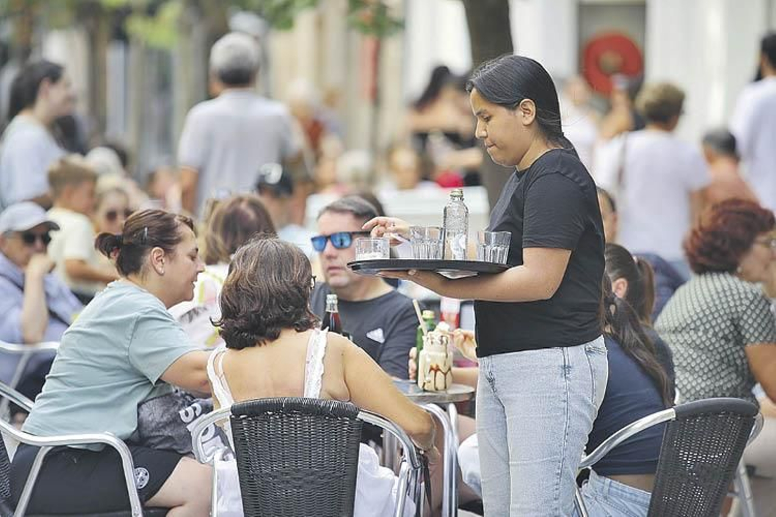 Camarera de un local de la ciudad, atendiendo a los clientes en la terraza del establecimiento.