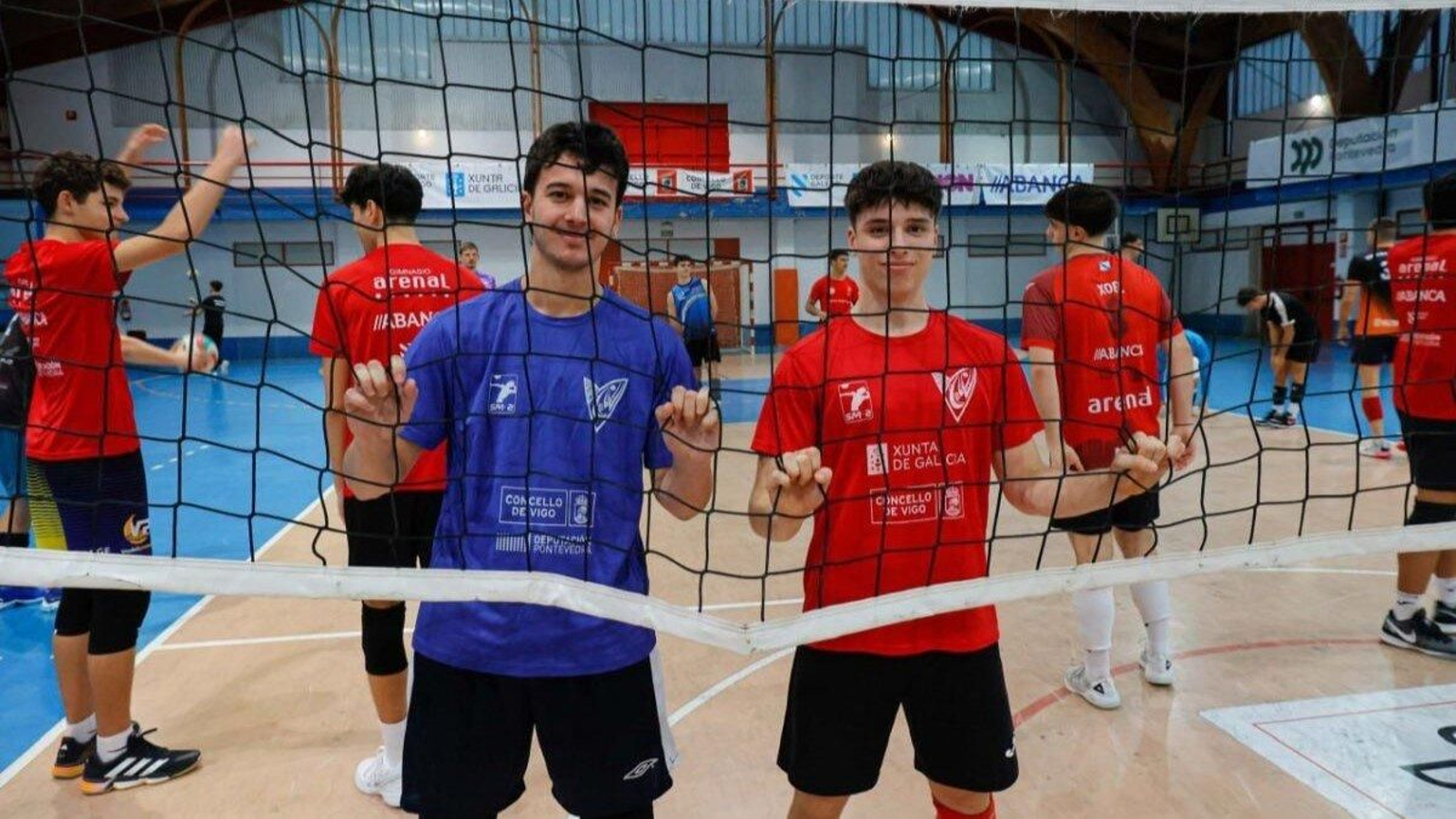 Los líberos Iván Sienes y Miguel Surís posan agarrando la red del pabellón de Coia antes del entrenamiento de ayer.