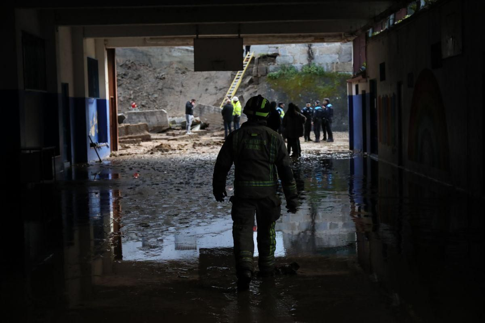 Un bombero accede al patio exterior, totalmente encharcado.