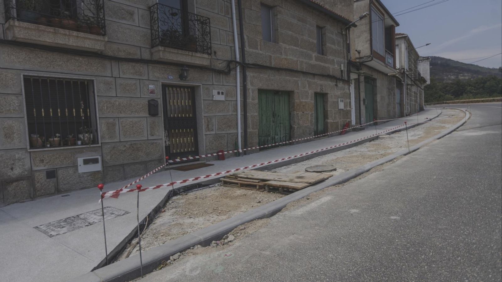 Zonas de aparcamiento, acordonadas y sin rematar, con el bordillo levantado.