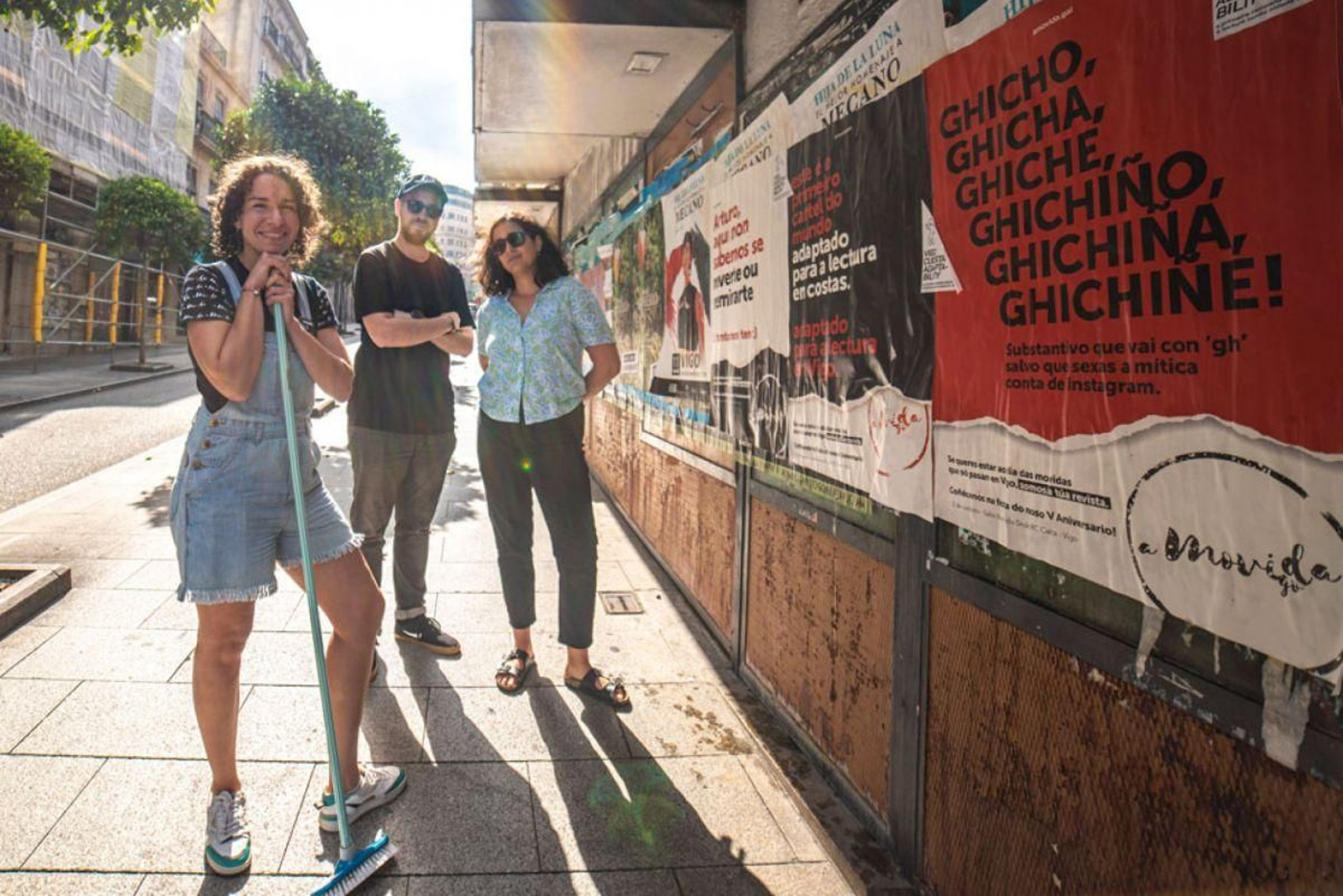 Los responsables de A Movida, durante la pegada de carteles.