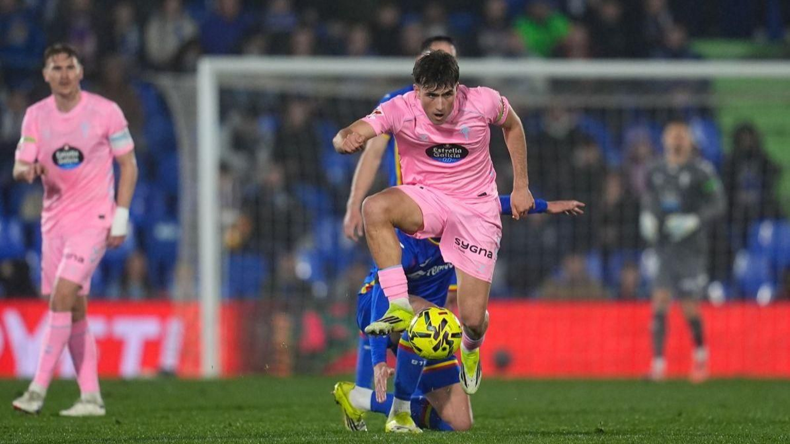 Javi Rodríguez arraca con la pelota con Radu observando al fondo.