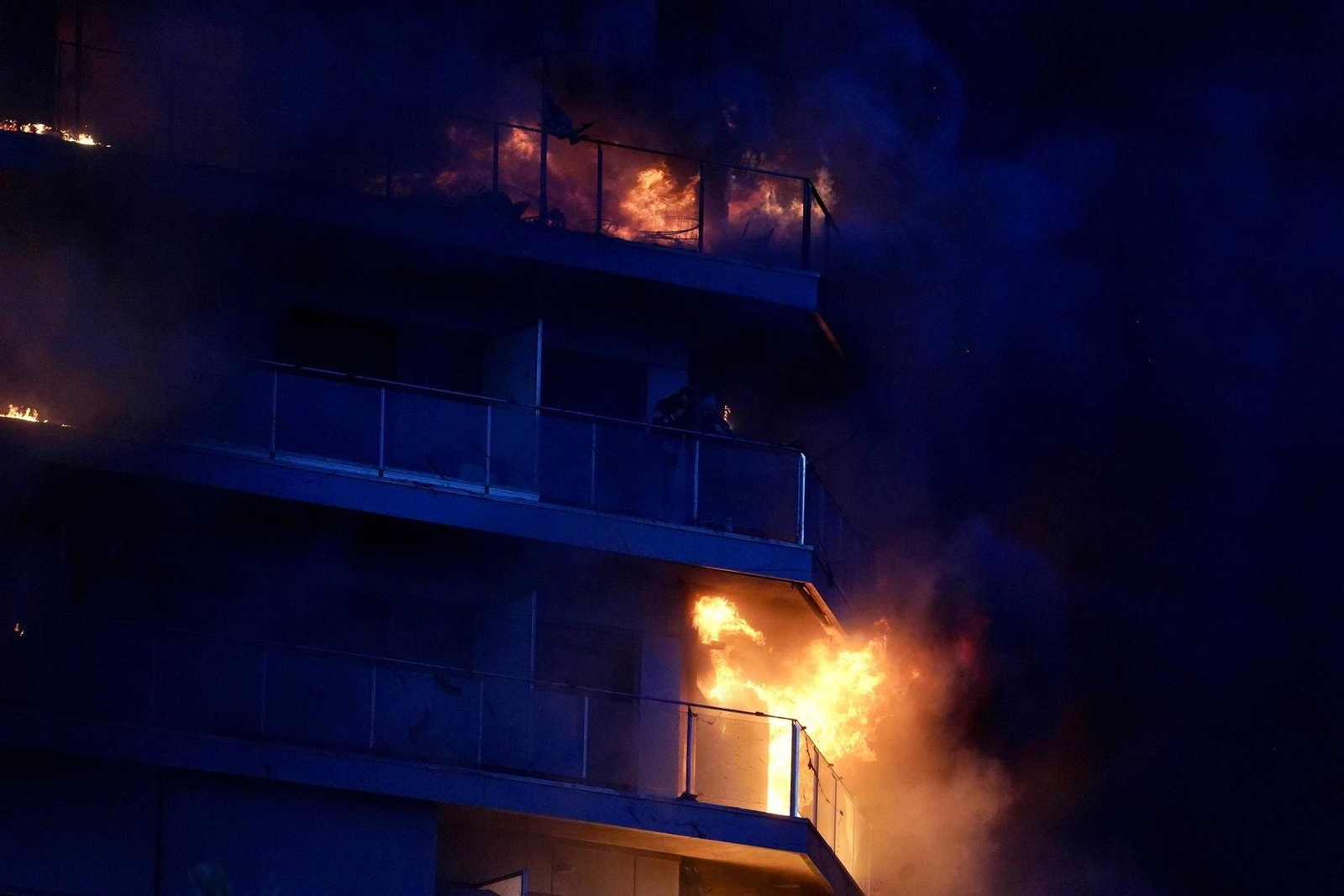 Dos personas en un balcón del edificio en llamas.