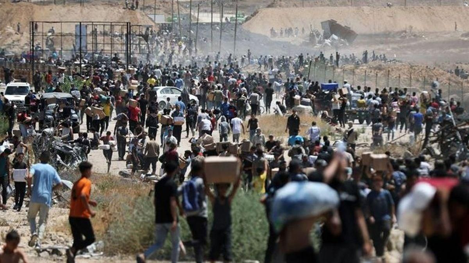 Un grupo de palestinos carga con ayuda entregada por GHF, en Al Bureij, en la Franja de Gaza.