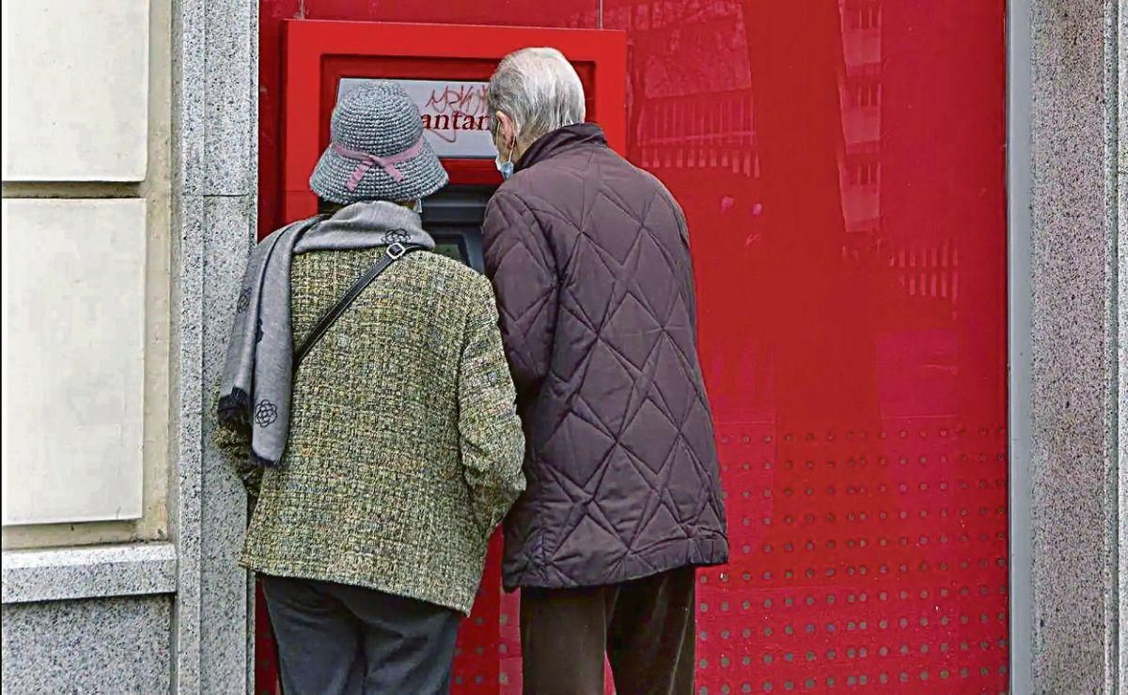 Una pareja de jubilados saca dinero en un cajero.