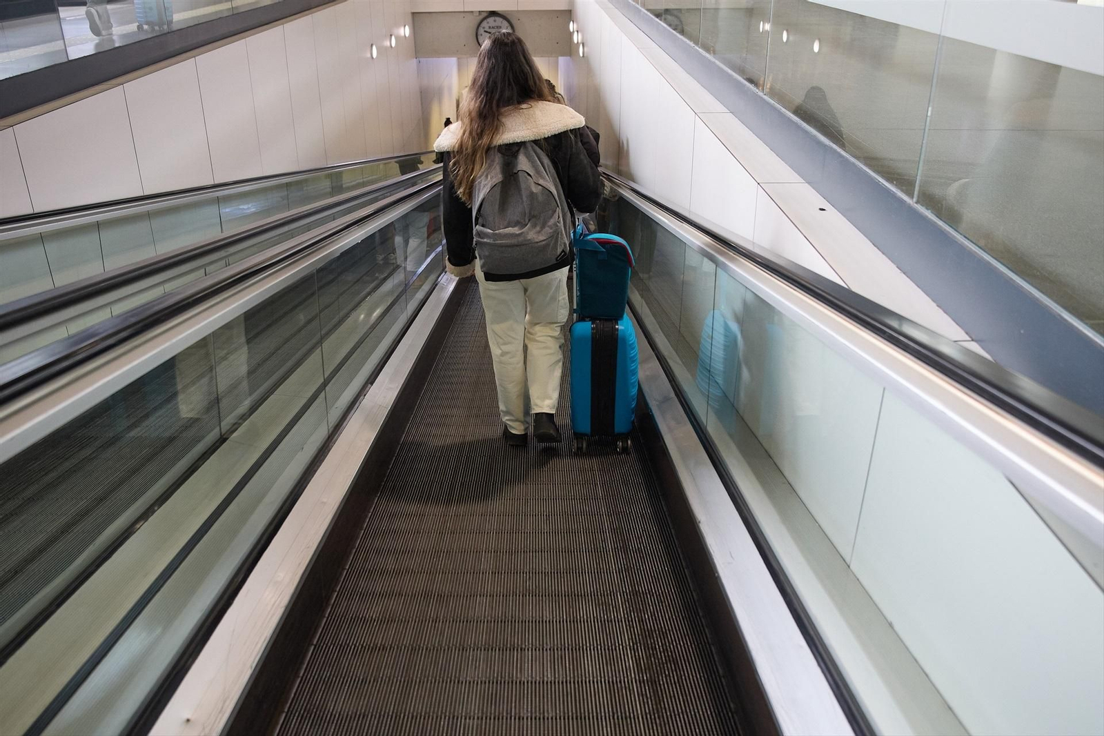 Una joven con una maleta camina por una cinta