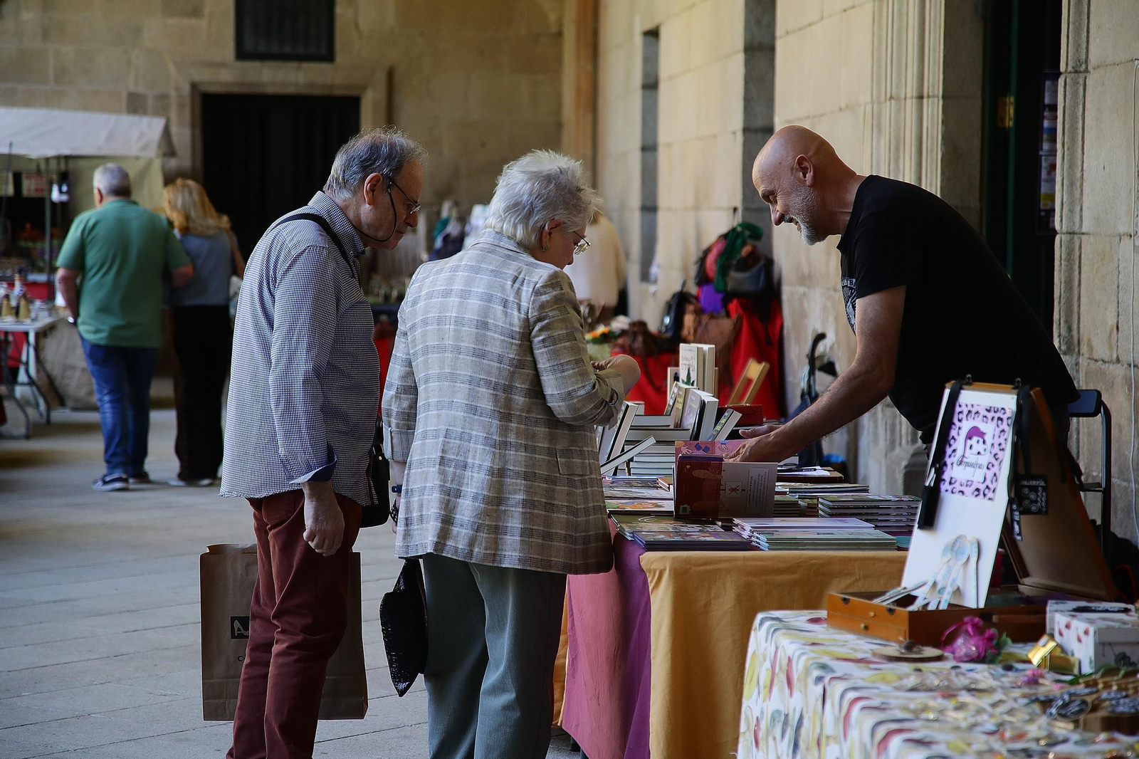 Dos visitantes se paran a ver un stand de libros en el Claustro de Celanova durante la Festa da Faba.
