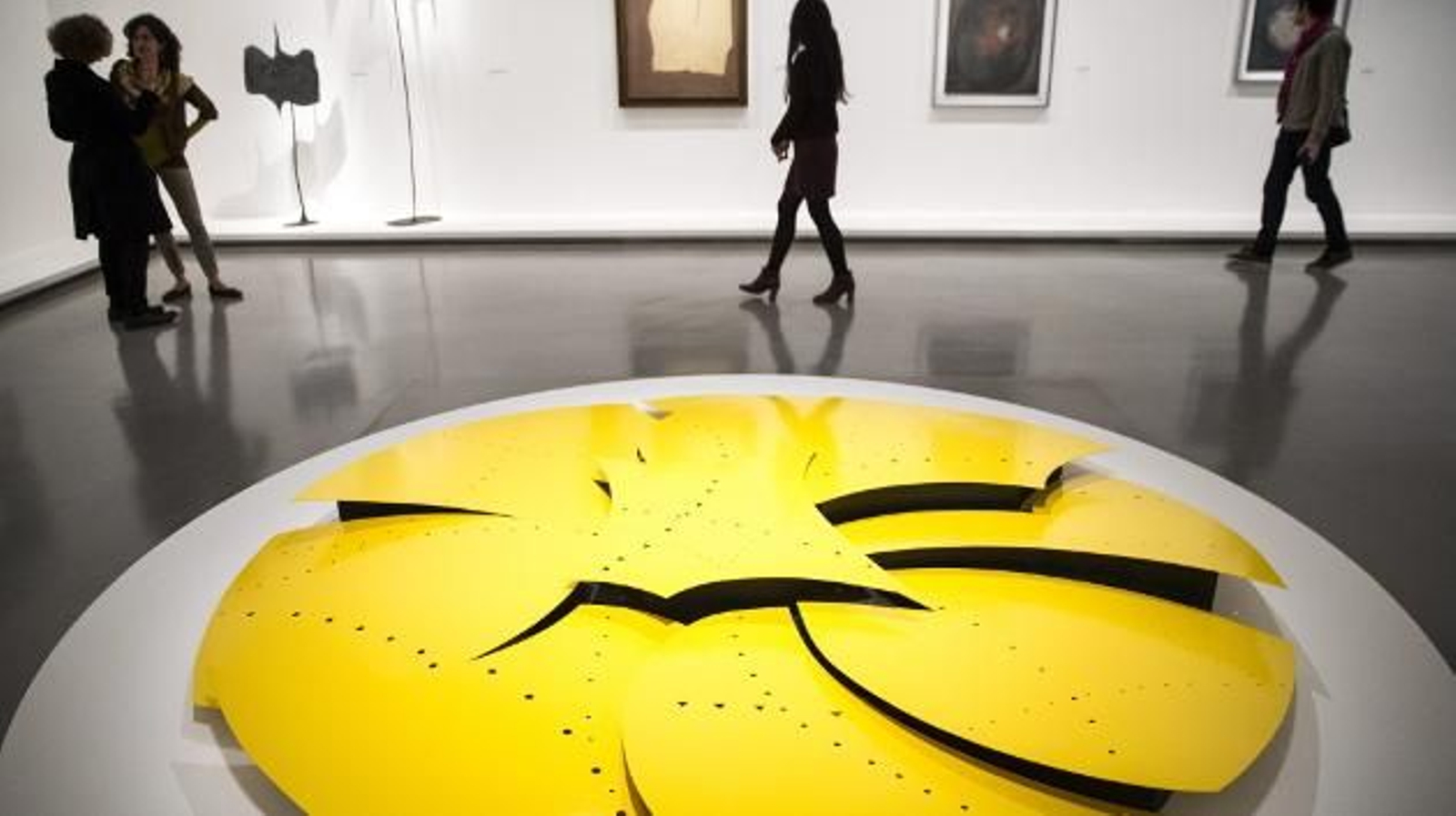 Varios visitantes caminan junto a la obra "Concetto Spaziale" (Concepto espacial), del artista italo-argentino Lucio Fontana