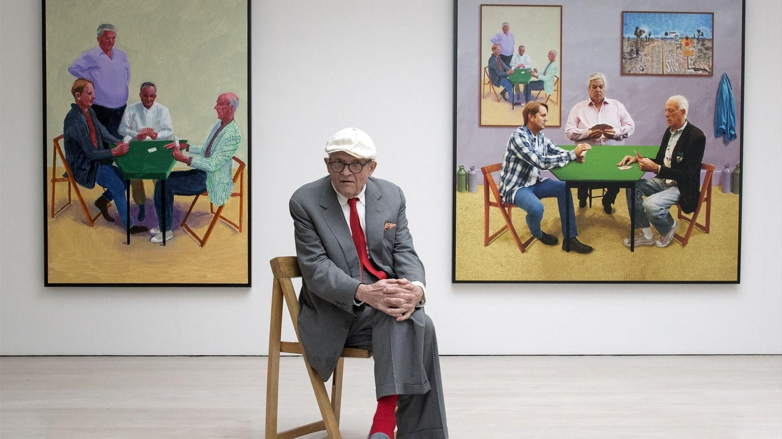 David Hockney posa ante una de sus exposiciones, reflejo de una trayectoria artística que transformó el arte contemporáneo durante más de seis décadas.