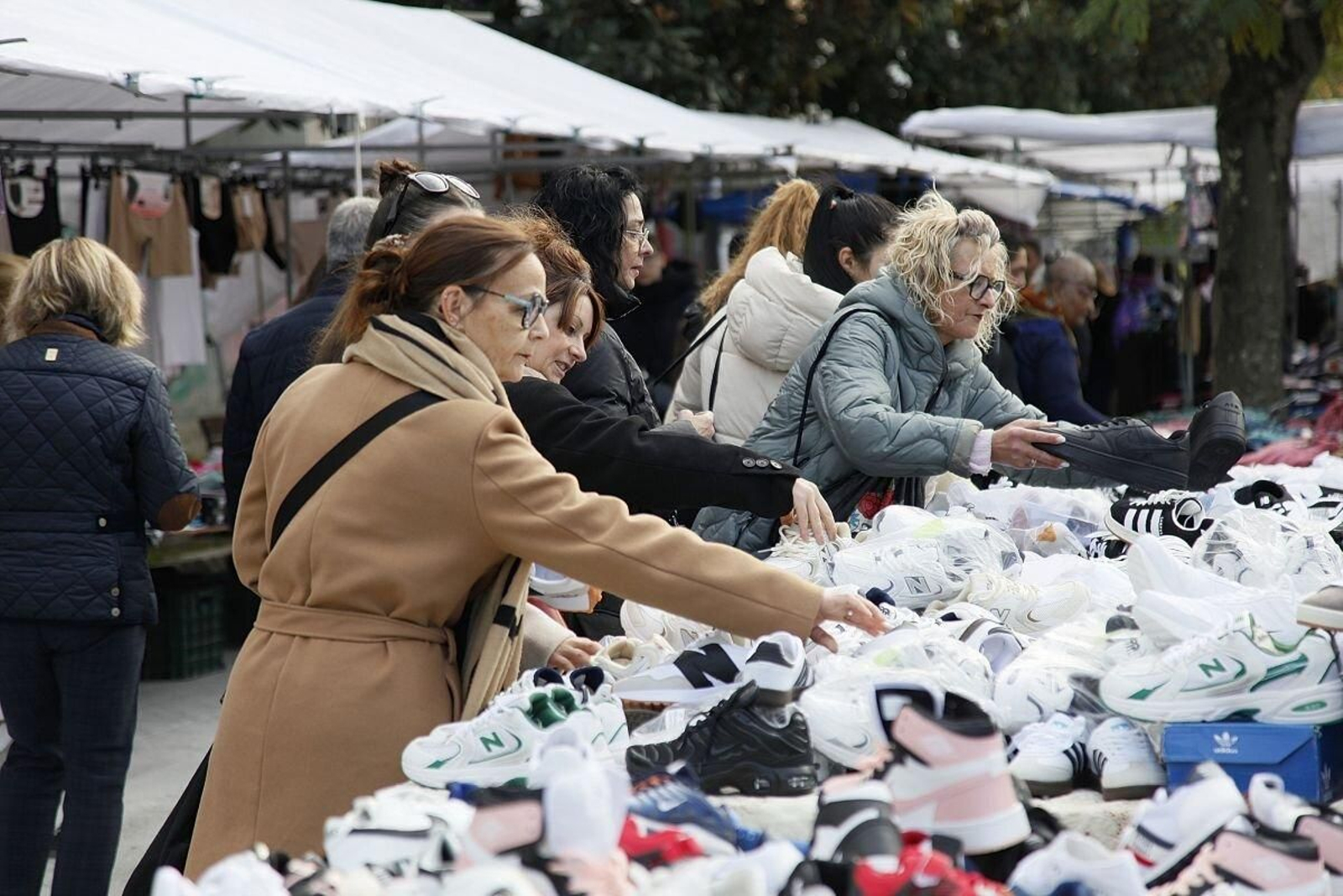 Un grupo de mujeres busca prendas en uno de los expositores de la feria.