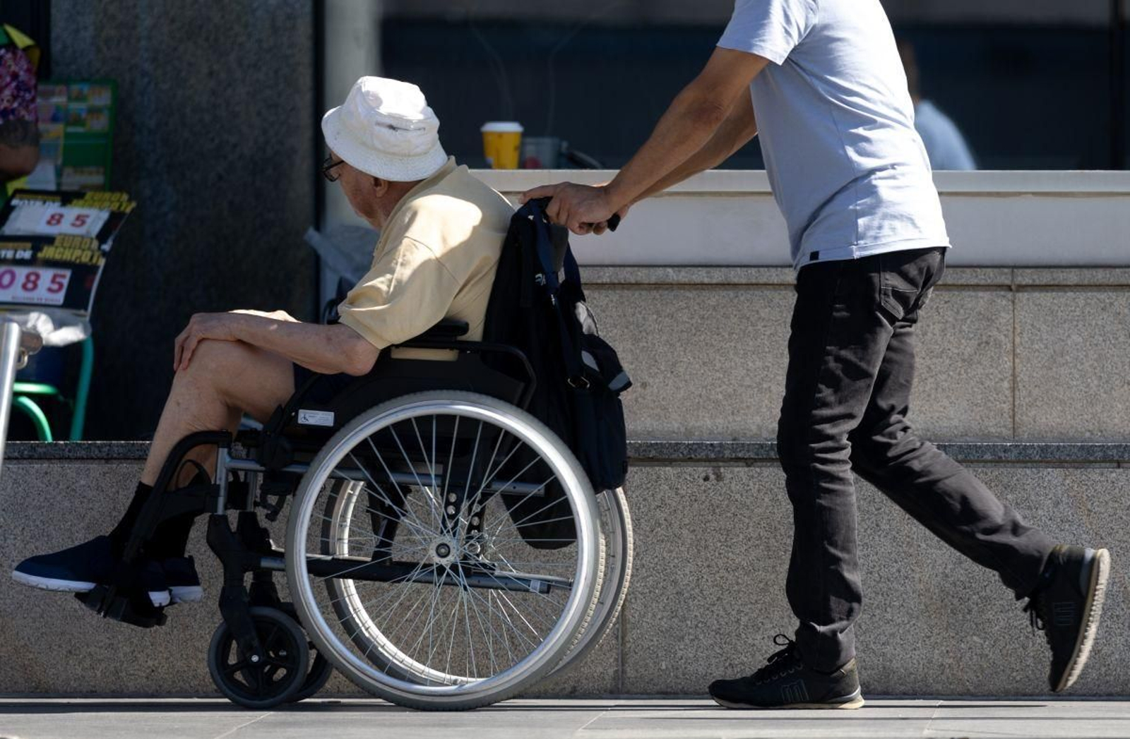 Una persona asiste a otra en silla de ruedas en Madrid.