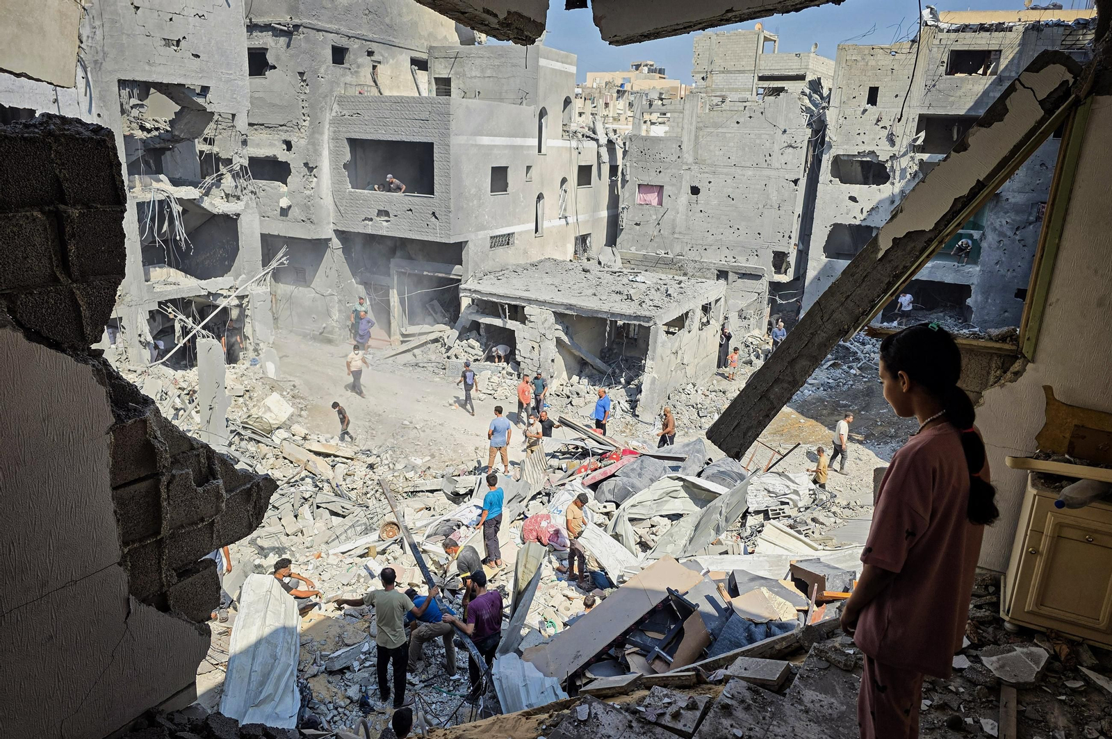 Palestinos entre ruinas después de que un ataque aéreo israelí destruyera sus casas.