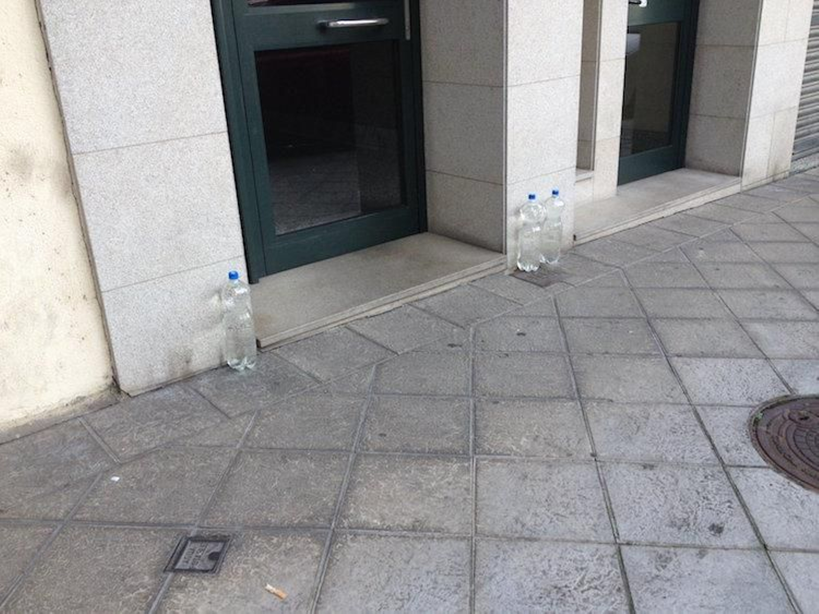 Botellas de agua guardando un portal de Bernardo Gonzalez Cachamuiña, en Ourense.
