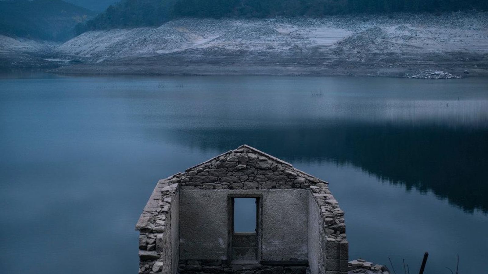 Vista de una vivienda del antiguo pueblo de Aceredo, en Lobios (Ourense) que quedó sepultado en la década de los noventa por las aguas del embalse de Lindoso y que volvió a emerger por el vaciado del embalse y la sequía. El proyecto de construcción del embalse nació de un acuerdo entre las dictaduras de Franco y Salazar y se ejecutó décadas después (1992), borró del mapa las casas de cuatro aldeas.El dictador Franco maltrató con persistencia las zonas rurales. Propició un gran éxodo e hizo insalvables los desequilibrios entre el campo y la ciudad. Su fiebre por construir pantanos que servían para abastecer de agua y electricidad a las grandes ciudades acabó con un sistema de vida. Familias como las de Aceredo se vieron obligadas a abandonar sus casas forzosamente y dejar sus negocios.