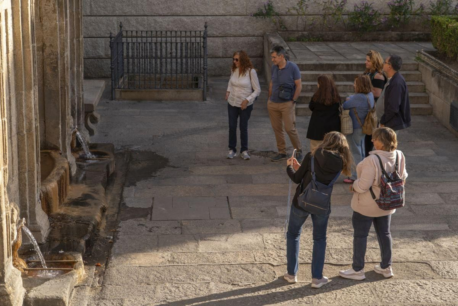Un grupo de turistas contempla la fuente de As Burgas, en un tour por la ciudad.
