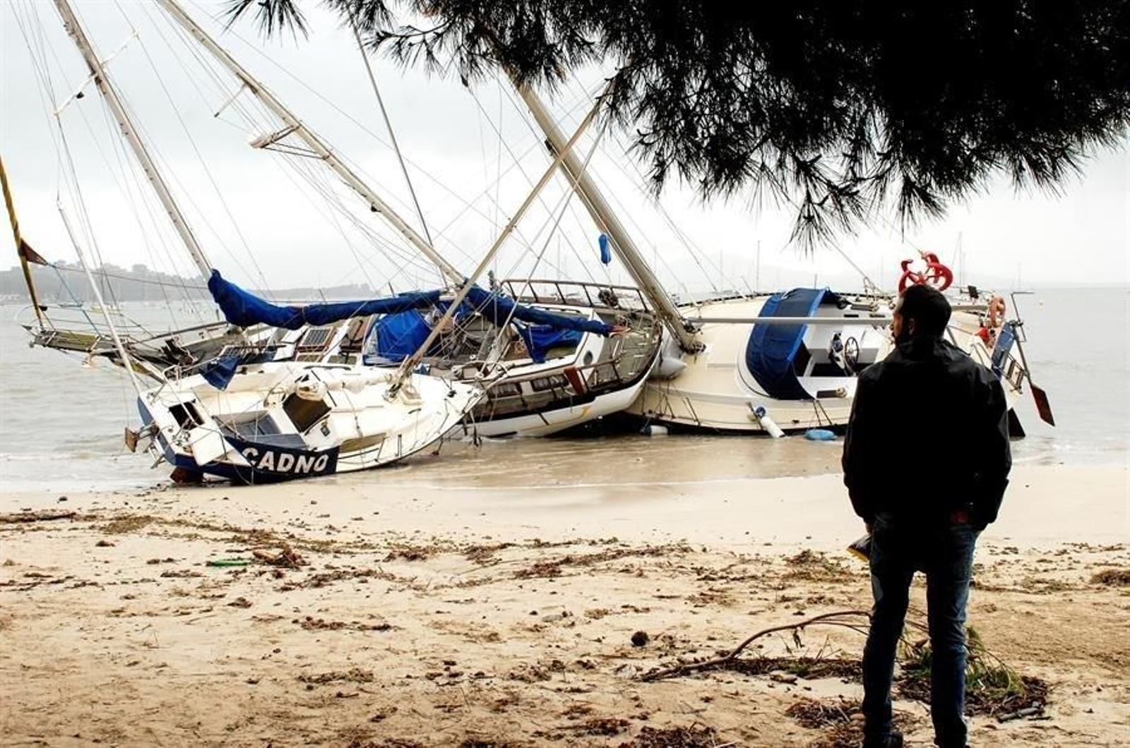 Un hombre mira tres embarcaciones varadas en Mallorca (EFE).