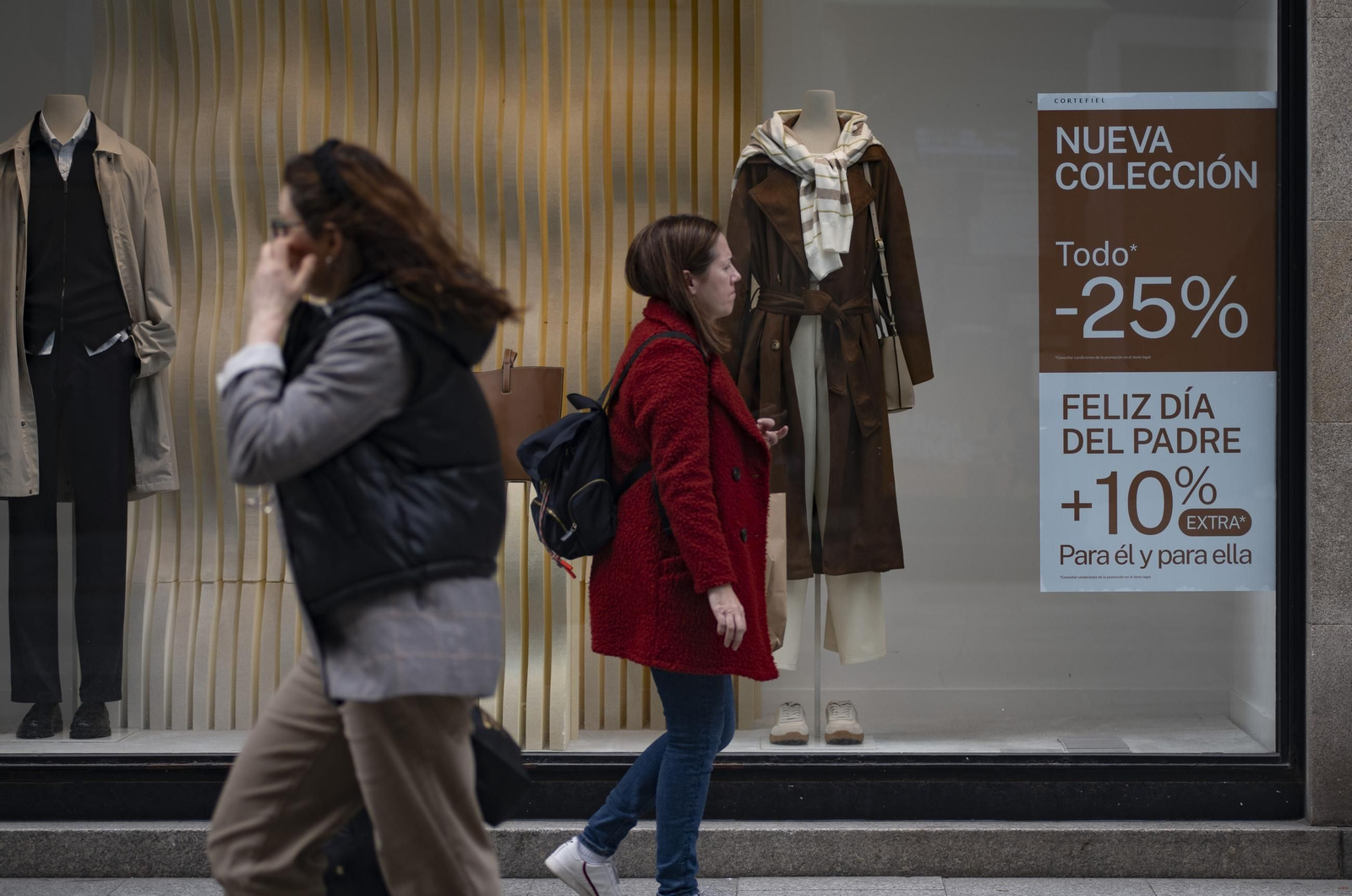 Dos personas pasan por delante de un cartel promocional del Día del Padre.
