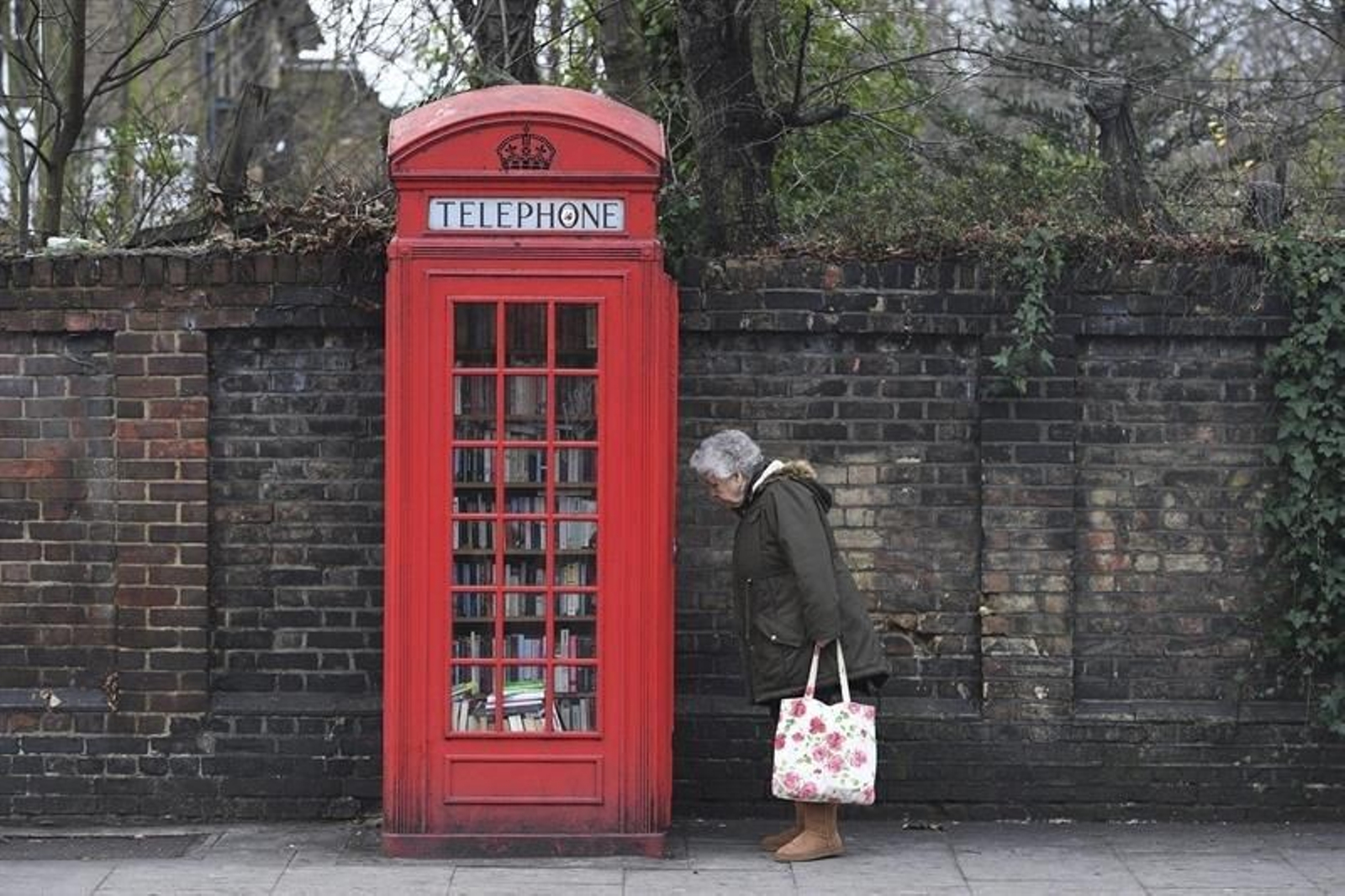 Una mujer observando una cabina telefónica 'reconvertida' en Londres.