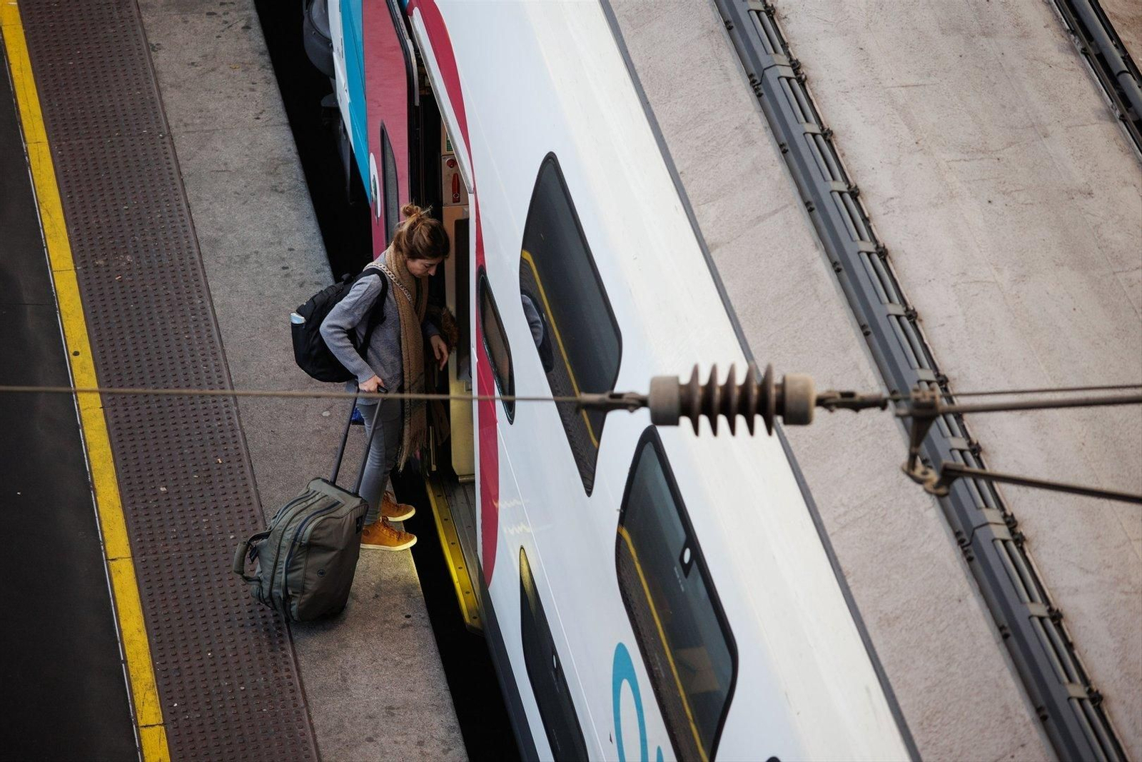 Una mujer entra en el tren con su maleta. // EP